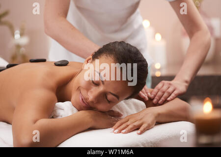 Portrait of young woman smiling béate heureusement tout en profitant de la thérapie en pierre en spa, copy space Banque D'Images