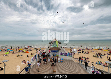 Bournemouth, Royaume-Uni. 4 août 2019. Temps couvert avec un ciel orageux n'a pas dissuader les foules de personnes bénéficiant d'Bourneomuth beach et nager dans la mer. Crédit : Thomas Faull/Alamy Live News Banque D'Images