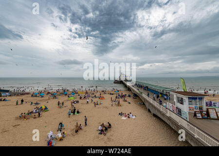 Bournemouth, Royaume-Uni. 4 août 2019. Temps couvert avec un ciel orageux n'a pas dissuader les foules de personnes bénéficiant d'Bourneomuth beach et nager dans la mer. Crédit : Thomas Faull/Alamy Live News Banque D'Images