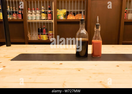 Deux bouteilles de sauce de soja et le piment fort sur une table en bois dans un restaurant asiatique ou chinois bar avec des boulettes Banque D'Images