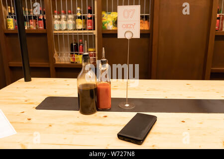 Espagne, Barcelone. - Le 27 juillet, 2019. Deux bouteilles de sauce de soja et le piment fort sur une table en bois dans un restaurant asiatique ou chinois bar avec des boulettes Oizy Banque D'Images