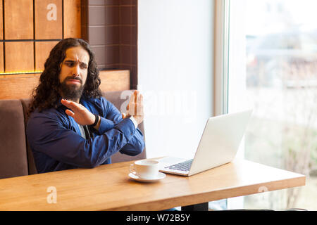 Arrêter de parler ! Portrait de jeune homme en colère adultes freelancer dans style casual assis dans un café et parler avec son ami dans le coffre, montrant sto Banque D'Images