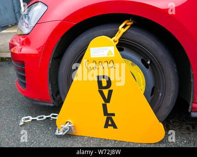 DVLA pince munie d'une roue de voiture UK rouge qui n'a pas payé la taxe de circulation ou de l'assurance contrôle technique annuel Banque D'Images