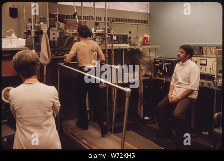 MINER DANS LE POUMON NOIR LABORATOIRE DE L'HÔPITAL RÉGIONAL DES APPALACHES DANS LA RÉGION DE BECKLEY, WEST VIRGINIA, TANDIS QUE L'OBJET D'ESSAIS SUR UN TAPIS ROULANT. Sa capacité pulmonaire et de la pulsation sont surveillés, ET DES ÉCHANTILLONS DE SANG SONT PRIS. Sur la gauche EST DELILA LAFON, QUI TIRE LES ÉCHANTILLONS DE SANG, ET EST L'ÉPOUSE D'UN MINEUR. Au DROIT EST JOHN ELLISON CHEF TECHNICIEN DE LABORATOIRE. Le sang sera vérifié de la concentration d'OXYGÈNE, Banque D'Images