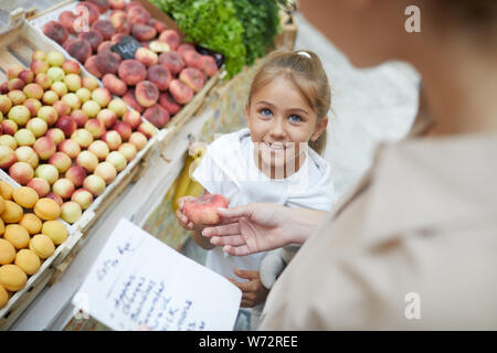 High angle portrait of cute little girl smiling at maman en faisant vos achats chez farmers market ensemble, copy space Banque D'Images