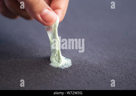 Close up hand dépose de chewing-gum collant noir ou de textiles Vêtements Banque D'Images