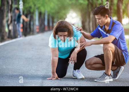 L'encouragement à faire de l'homme asiatique grosse femme qui fatigué et assis sur sol Banque D'Images