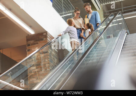 Portrait of happy young famille avec deux enfants en descendant l'escalator dans shopping mall, copy space Banque D'Images