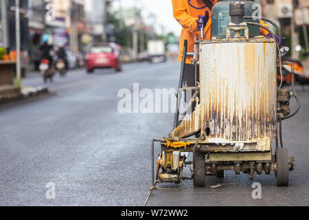 Travaillant en plein air : Homme à l'aide de la machine pour rendre la circulation sur la route bande de ligne Banque D'Images