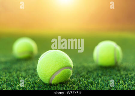 Close up balle de tennis sur gazon vert avec fond effet coucher du soleil Banque D'Images