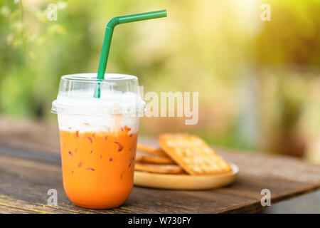 Thé glacé Thai dans du plastique transparent tasse servi sur table en bois dans la région de Garden Cafe. Concept menu glace Banque D'Images