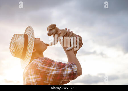 Les jeunes agriculteurs d'Asie en jouant avec son petit brun chiot dans la soirée après le travail. Happy farm concept Banque D'Images