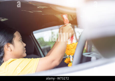 Femme thaïlandaise avec guirlande de fleurs jaune dans la main et prier dans la nouvelle voiture pour la chance, la sécurité dans un style thaï Banque D'Images