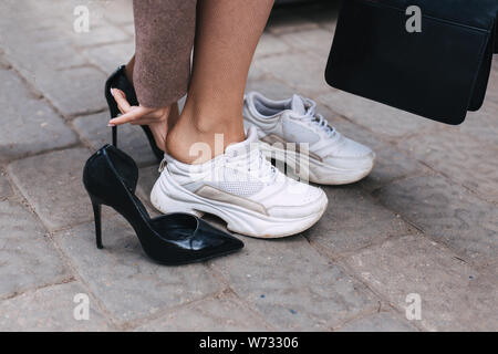 Femme d'affaires pieds nus en secouant des chaussures de haut talon pour un confort optimal sneaker Banque D'Images