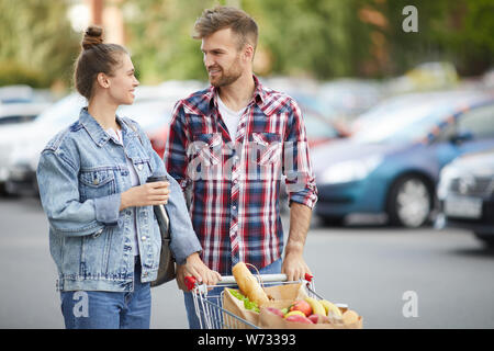 Taille portrait de jeune couple contemporain shopping en stationnement après l'épicerie, copy space Banque D'Images