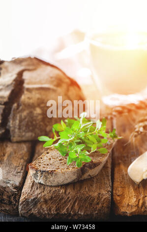 Un morceau de pain de seigle avec un bouquet de thym et un verre de lait frais en verre sur un support en bois. Farmer's Petit-déjeuner tôt. Copier l'espace. Banque D'Images