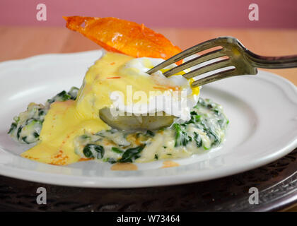 Oeufs Sardou - un œuf poché servi sur un fond d'artichaut sur un lit d'épinards à la crème, garni de sauce hollandaise et une peau de tomate frite en garniture. Banque D'Images