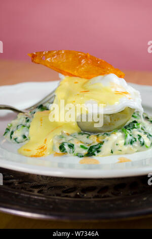 Oeufs Sardou - un œuf poché servi sur un fond d'artichaut sur un lit d'épinards à la crème, garni de sauce hollandaise et une peau de tomate frite en garniture. Banque D'Images