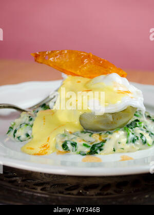 Oeufs Sardou - un œuf poché servi sur un fond d'artichaut sur un lit d'épinards à la crème, garni de sauce hollandaise et une peau de tomate frite en garniture. Banque D'Images