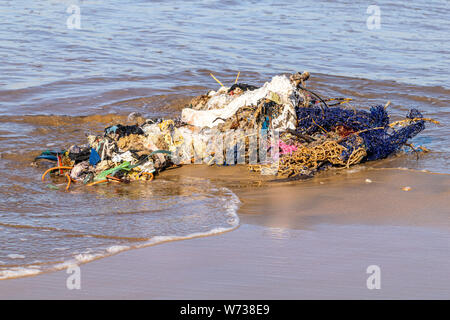 Les filets de pêche et la pollution déchets rejetés par l'Océan Atlantique sur une plage de sable fin à Agadir, Maroc Banque D'Images