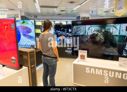 Femme à la recherche de nouveaux Samsung 4k haute définition télé des courbes store électrique Banque D'Images