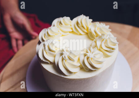 Décorées avec des baies d'une pâtisserie gâteau biscuit avec crème blanche. Cake se dresse sur une table en bois. Le concept de pâtisserie maison, la cuisson des gâteaux. Banque D'Images