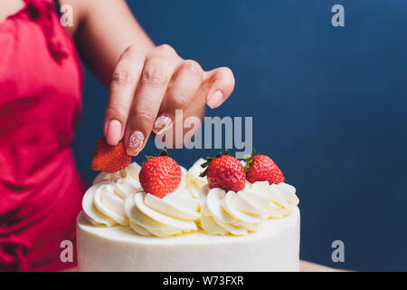 Décorées avec des baies d'une pâtisserie gâteau biscuit avec crème blanche. Cake se dresse sur une table en bois. Le concept de pâtisserie maison, la cuisson des gâteaux. Banque D'Images