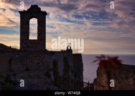 Clocher en pierre au-dessus de la mer dans le soleil couchant, Peschici, péninsule du Gargano, Italie Banque D'Images