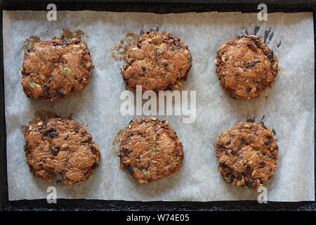 Six haricots noirs vegan burgers sur une plaque recouverte de papier sulfurisé, fraîchement sorti du four. Banque D'Images