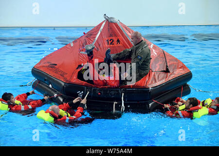 Enge Sande, Allemagne. 19 juillet, 2019. Sous la direction du professeur René Ploegert (debout), les techniciens à l'étranger former comment survivre en mer dans le centre de formation maritime Offtec. L'entraînement de survie fait partie de la programme obligatoire pour les techniciens sur les éoliennes. Crédit : Carsten Rehder/dpa/Alamy Live News Banque D'Images