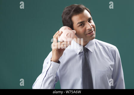 Businessman holding piggy bank par l'oreille Banque D'Images