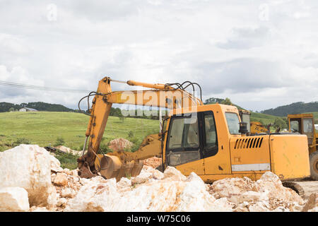 Le tracteur sur de gros des pierres sur les montagnes avec de la pelouse et des arbres paysage avec belle journée Banque D'Images