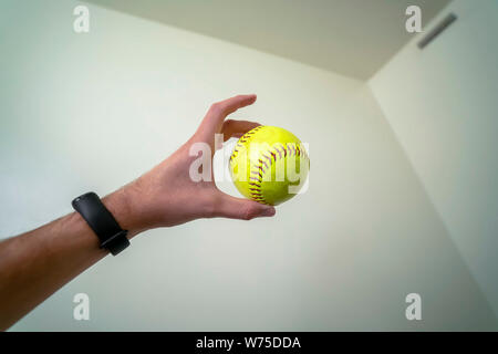 Close up of hand holding un cuir vert jaune rouge au baseball avec stictches Banque D'Images