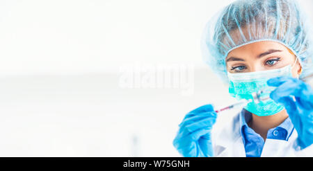 Femme médecin travaillant avec aiguille et ampoule de médicament. Un scientifique fait des vêtements stériles dans un vaccin médicament. Banque D'Images