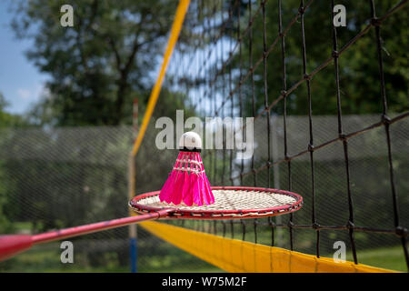 Volant à plumes rose sur un filet de badminton avec raquettes Banque D'Images