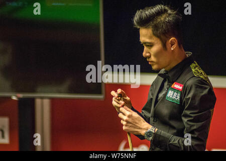 Yupeng Cao de Chine les craies son cue qu'il estime un shot de Ricky Walden de l'Angleterre dans leur quart de finale lors de l'Ope écossais 2017 Dafabet Banque D'Images