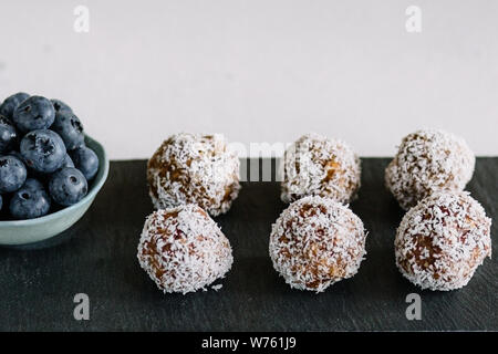 Boules d'énergie maison avec noix de coco et bleuets. Nourriture saine pour les enfants et les végétaliens, les bonbons se substituent. Gros plan. Banque D'Images