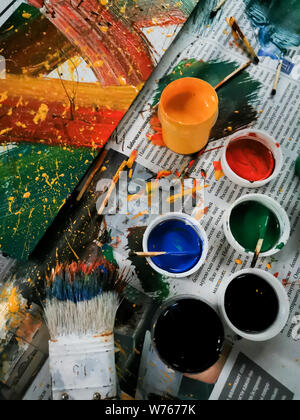 Les couleurs lumineuses colorées, pinceaux et la peinture abstraite sur fond de journal. Boîtes de différentes couleurs et l'art contemporain Banque D'Images