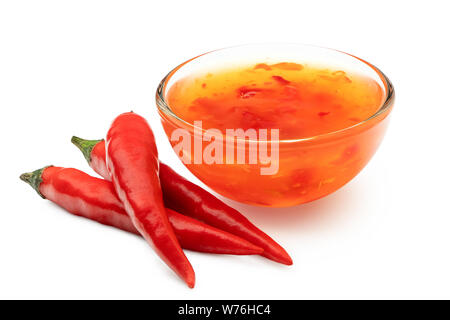 Sweet chili sauce dans un bol en verre à côté de trois piments rouge isolé sur blanc. Banque D'Images