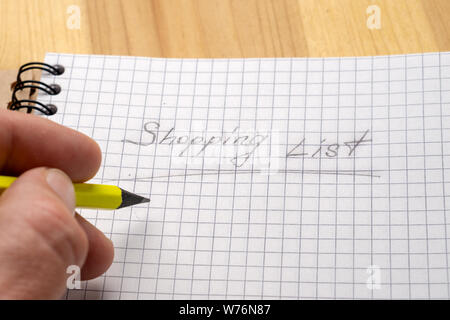Un homme écrit au crayon jaune sur un ordinateur portable. Signer la liste d'Achats Banque D'Images