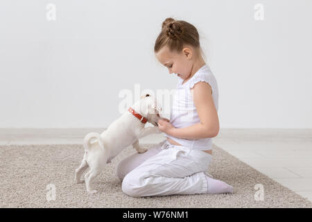 Animal de compagnie, les enfants et animaux - concept enfant fille assise sur le sol et l'alimentation chiot Banque D'Images