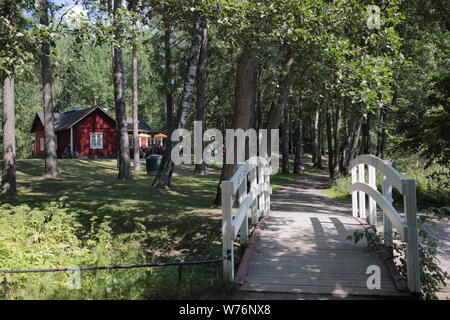 Pont de bois dans le parc, Ullas Vuosaari, Helsinki, Finlande. Ullas villa construite à la mi-1800 et a servi aujourd'hui qu'un café est visible sur la gauche Banque D'Images