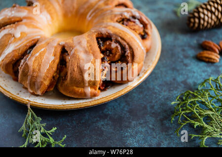 Bague plateau suédois gâteau de Noël à la cannelle, les pacanes et les raisins secs sur une chaude chandail tricoté. Le concept d'ambiance vacances d'hiver et de boulangerie. Banque D'Images