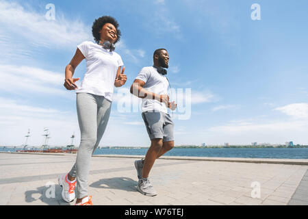 Cheerful Couple Afro le long de rivière en ville, Low-Angle Shot Banque D'Images