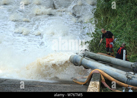 Vidange de l'eau des tuyaux du réservoir d'Toddbrook près du village de Whaley Bridge, Derbyshire, après qu'il a été endommagé d'une forte pluie. Banque D'Images