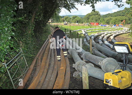 Vidange de l'eau des tuyaux du réservoir d'Toddbrook près du village de Whaley Bridge, Derbyshire, après qu'il a été endommagé d'une forte pluie. Banque D'Images