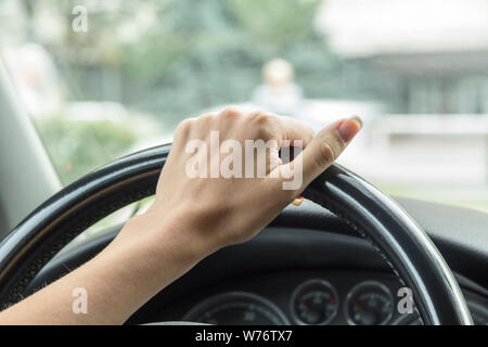 La main d'une fille avec une manucure élégant se trouve sur le guidon dans un salon de voiture Banque D'Images