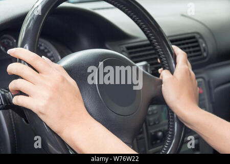 La fille avec la manucure ne cesse de mains sur le volant de la voiture Banque D'Images