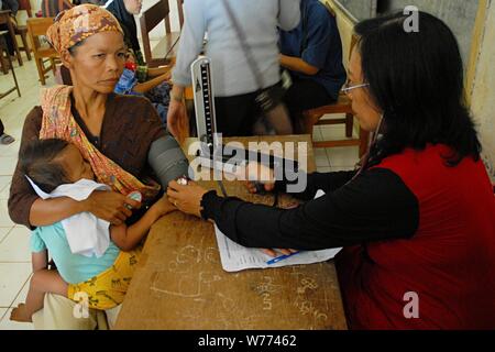 Bogor, Java ouest, Indonésie - Août 2019 : un médecin bénévole vérifie la pression artérielle d'une femme qu'un garçon dans un village sous-développé. Banque D'Images