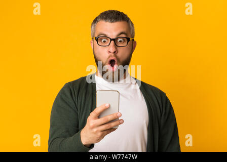 Choqué bel homme regardant son portable Banque D'Images